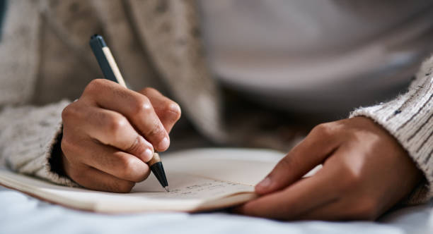 Image of a woman wearing a grey cardigan and writing in a journal